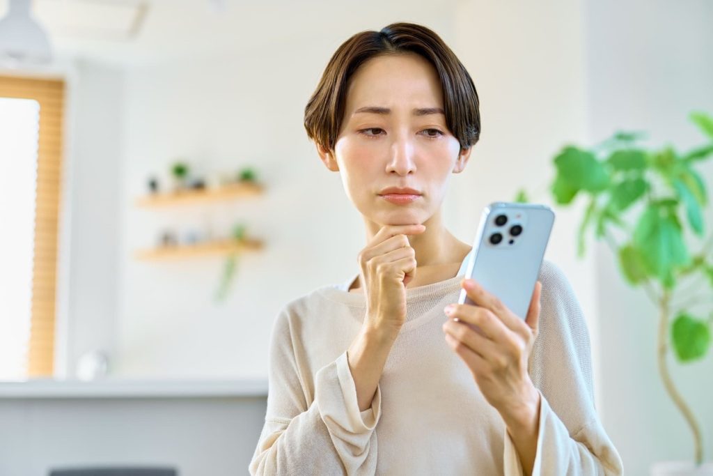 スマホを見て悩む女性