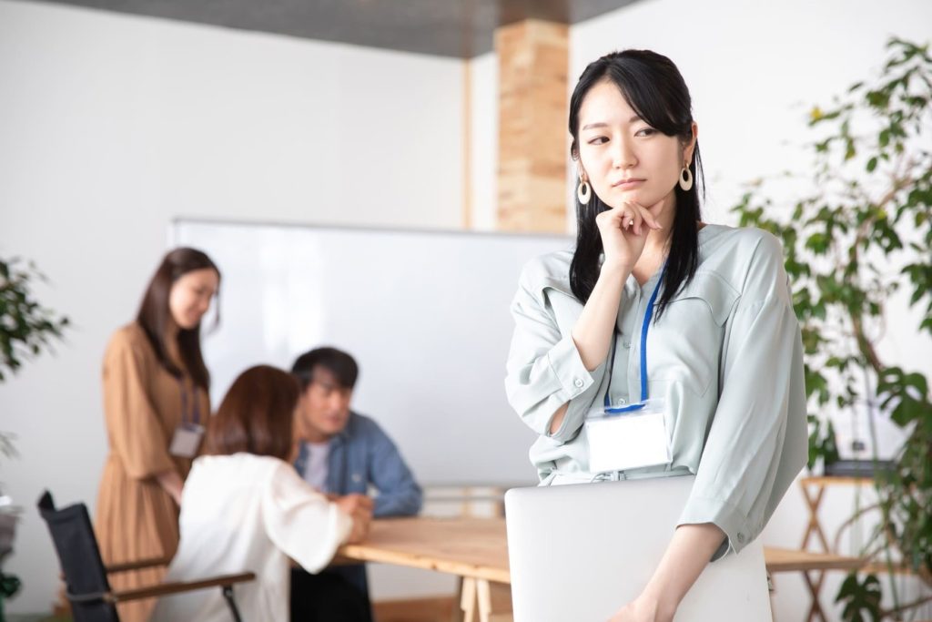 職場の同僚を見て悩む女性