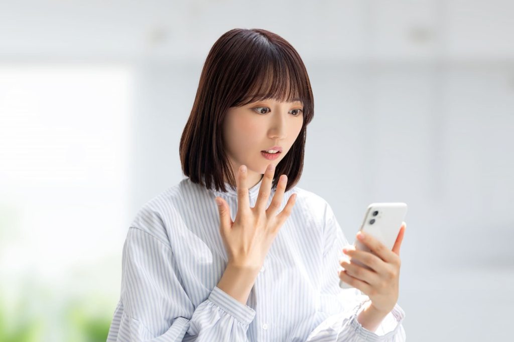 スマートフォンを見て驚く女性